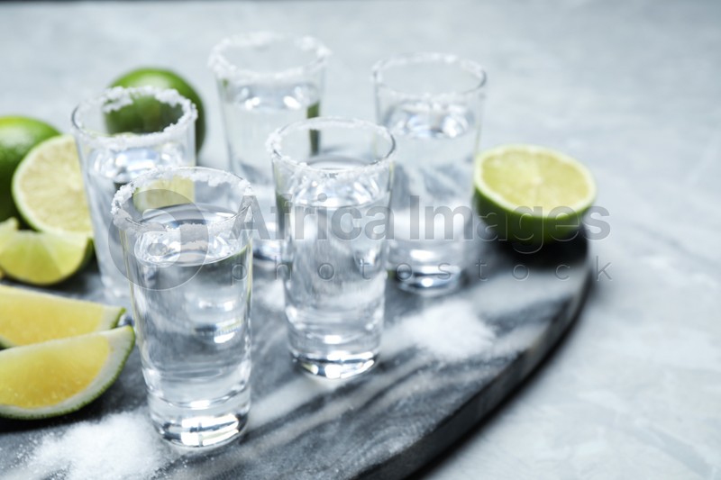 Mexican Tequila shots, lime slices and salt on grey marble table