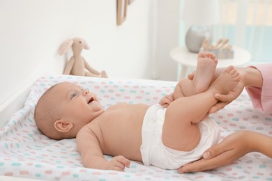 Mother changing her baby's diaper on table at home