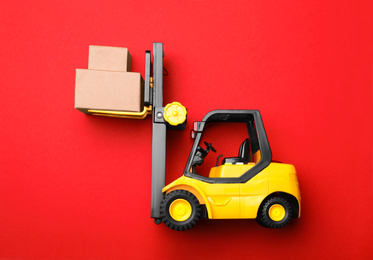 Top view of toy forklift with boxes on red background. Logistics and wholesale concept