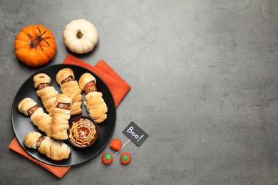 Spooky sausage mummies for Halloween party served on grey table, flat lay. Space for text