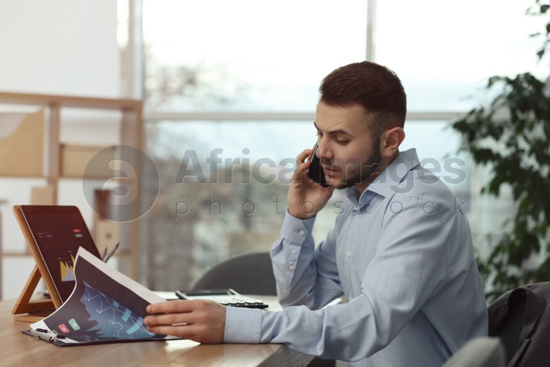Forex trader talking on phone while working in office