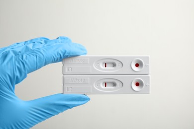 Doctor in gloves holding disposable express tests for hepatitis on white background, closeup
