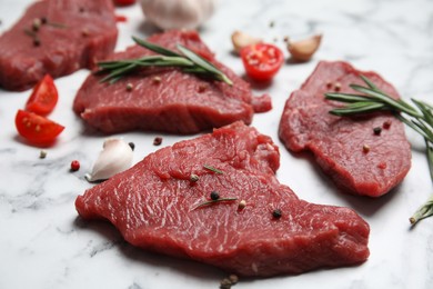 Fresh raw meat steaks and spices on white marble table, closeup