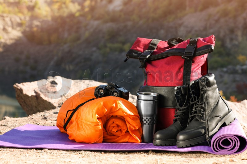 Set of camping equipment with sleeping bag on ground outdoors