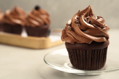 Delicious chocolate cupcake with cream and crumbles on light grey table, closeup. Space for text