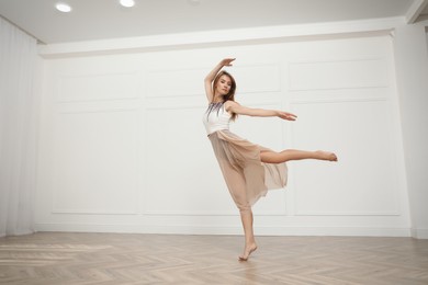 Beautiful professional dancer practicing moves in studio
