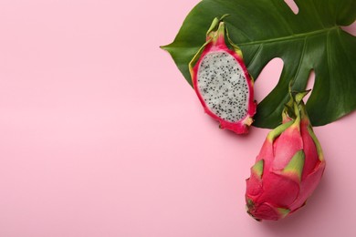 Photo of Delicious cut and whole white pitahaya fruits with green leaf on light pink background, flat lay. Space for text