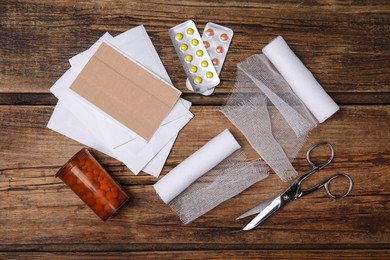 White bandage rolls and medical supplies on wooden table, flat lay