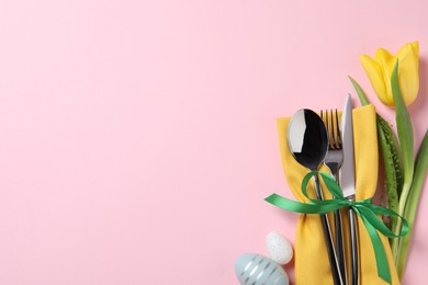 Photo of Cutlery set, Easter eggs and tulip on pale pink background, flat lay with space for text. Festive table setting