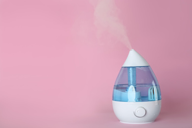 Modern air humidifier on pink background. Space for text