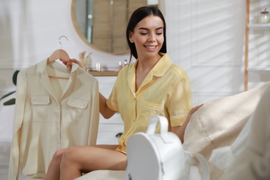 Young woman choosing clothes for work day at home. Morning routine