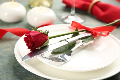 Beautiful table setting for Valentine's Day dinner with rose on wooden background, closeup