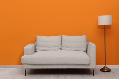 Photo of Comfortable sofa and stylish lamp indoors. Interior design