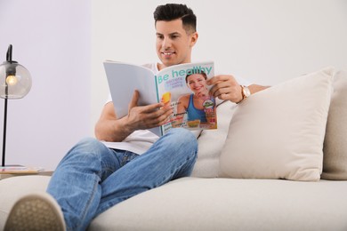 Man reading magazine on sofa in living room