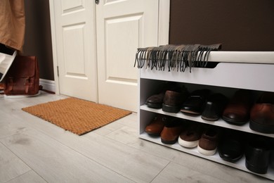 Shelving unit with shoes and door mat in hall