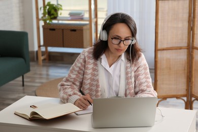 Woman with modern laptop and headphones learning at home
