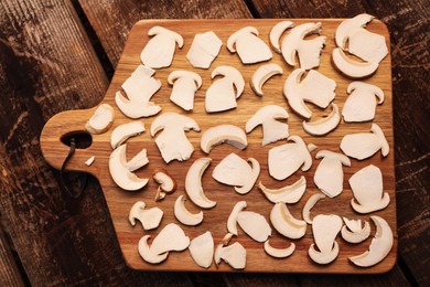Board with slices of mushrooms on wooden table prepared for natural dehydration, top view