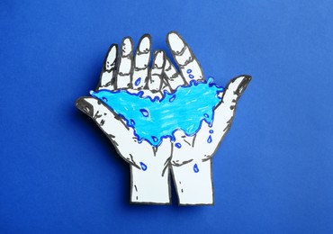 Photo of Hands with water paper figure on blue background, top view. Save water concept