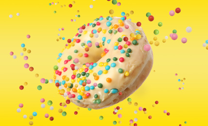 Image of Sweet delicious glazed donut falling on yellow background