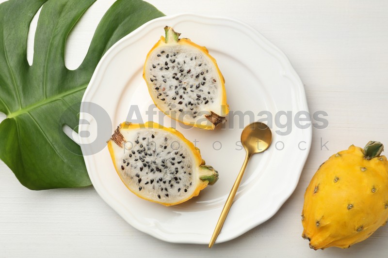 Delicious dragon fruits (pitahaya) and tropical leaf on white wooden table, flat lay