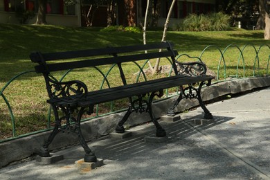 Photo of Beautiful old black bench near pathway in park