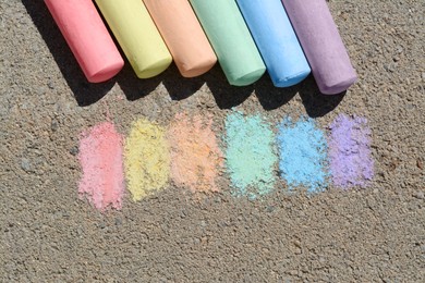Colorful chalk sticks and strokes on asphalt outdoors, flat lay