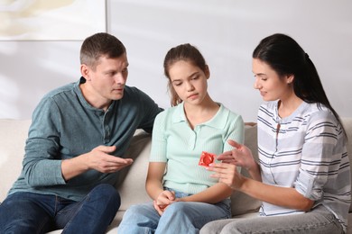 Parents talking with their teenage daughter about contraception at home. Sex education concept