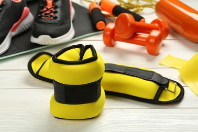 Yellow weighting agents and sport equipment on white wooden table