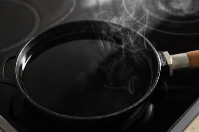 Photo of Frying pan with hot used cooking oil on stove, closeup