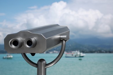 Photo of Metal tower viewer installed near sea, space for text. Mounted binoculars