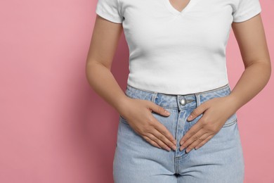 Young woman suffering from menstrual pain on pink background, closeup