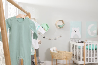 Cozy baby room interior, focus on wooden clothes rack