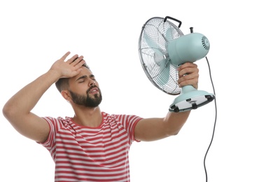 Man with fan suffering from heat on white background. Summer season