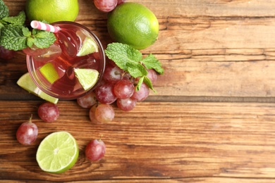 Refreshing drink with soda water, grapes, lime and mint on wooden table, flat lay. Space for text