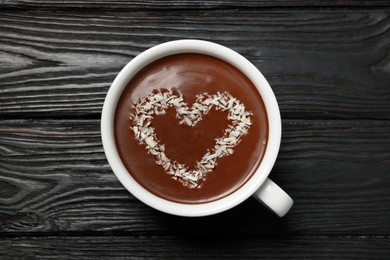 Photo of Cup of hot chocolate with heart shaped decoration on black wooden table, top view