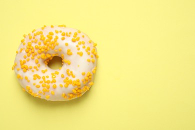 Photo of Delicious glazed donut on yellow background, top view. Space for text