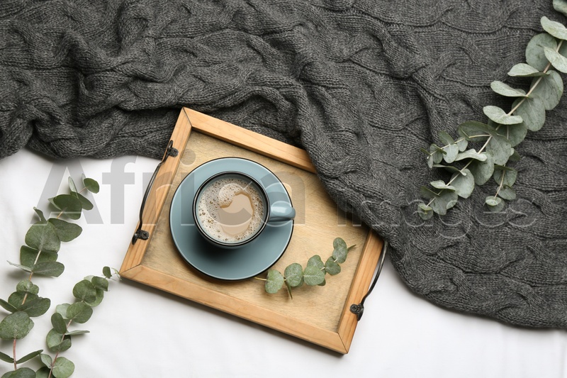 Flat lay composition with coffee and warm plaid on white bedsheet
