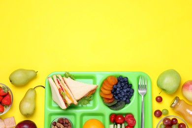 Flat lay composition with serving tray and tasty healthy food on yellow background. Space for text