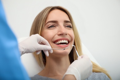 Doctor examining patient's teeth on light background, closeup. Cosmetic dentistry