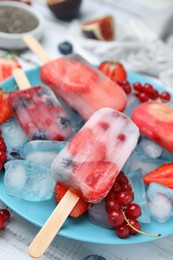 Photo of Tasty refreshing fruit and berry ice pops on plate, closeup