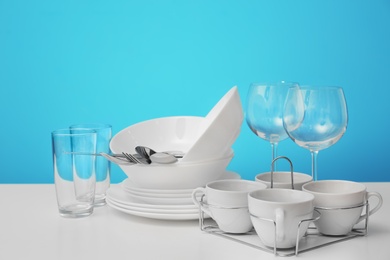 Set of clean dishware on table against color background