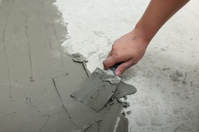 Worker with spatula applying adhesive mix for tiles on floor, closeup