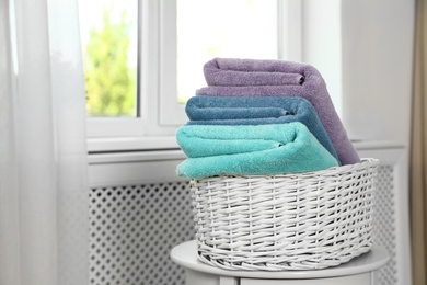 Basket with clean soft towels on table near window. Space for text