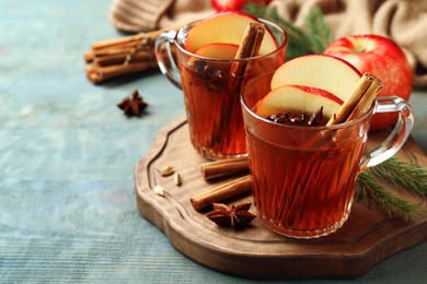 Aromatic hot mulled cider on light blue wooden table. Space for text