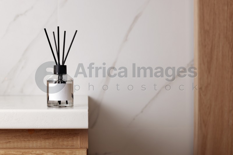 Aromatic reed air freshener on white table indoors, space for text