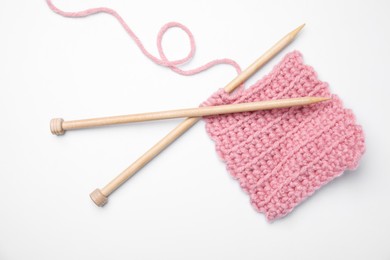 Pink knitting and wooden needles on white background, top view