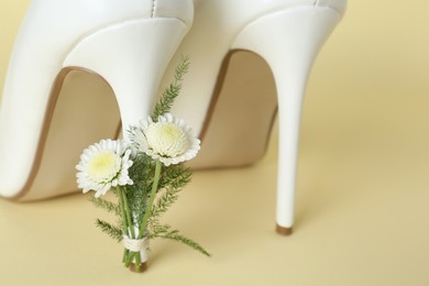 Stylish women's high heeled shoes with beautiful flowers on yellow background, closeup