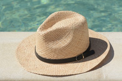Stylish hat near outdoor swimming pool on sunny day. Beach accessory