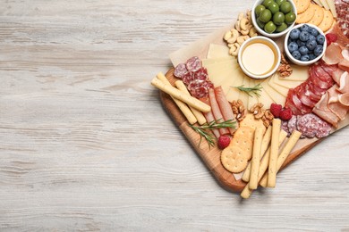 Tasty parmesan cheese and other different appetizers on white wooden table, top view. Space for text