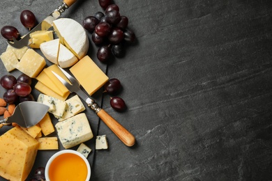 Cheese platter with specialized knives and fork on dark table, top view. Space for text